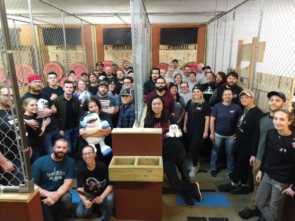 A group of axe throwers standing inside the lanes at Total Axe for a group picture